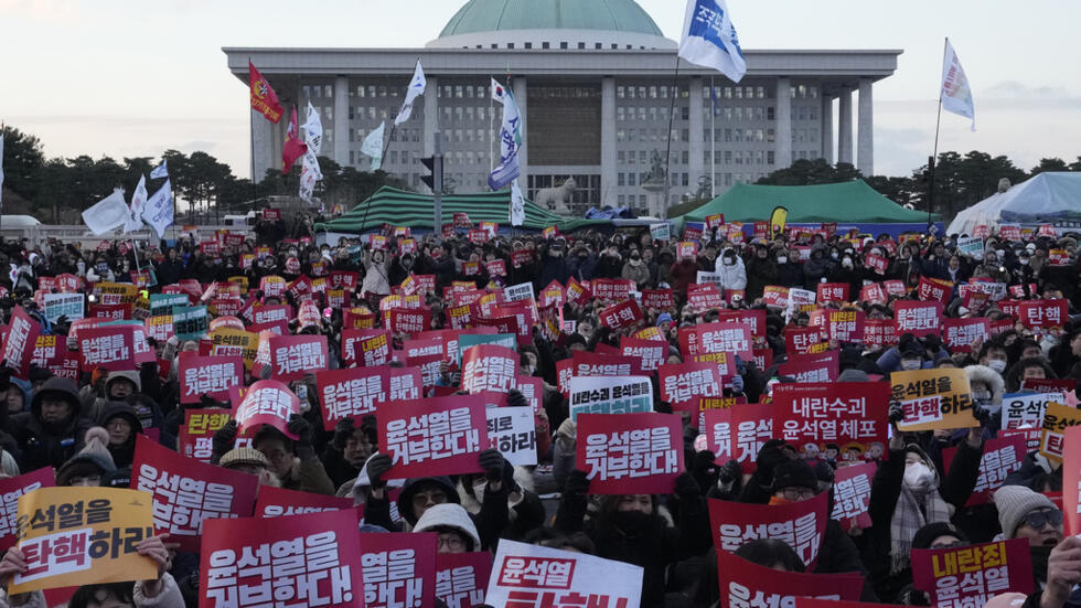 Manifestantes em protestos com diversos cartazes pedindo o impeachment e prisão do Presidente Yoon Suk Yeol.